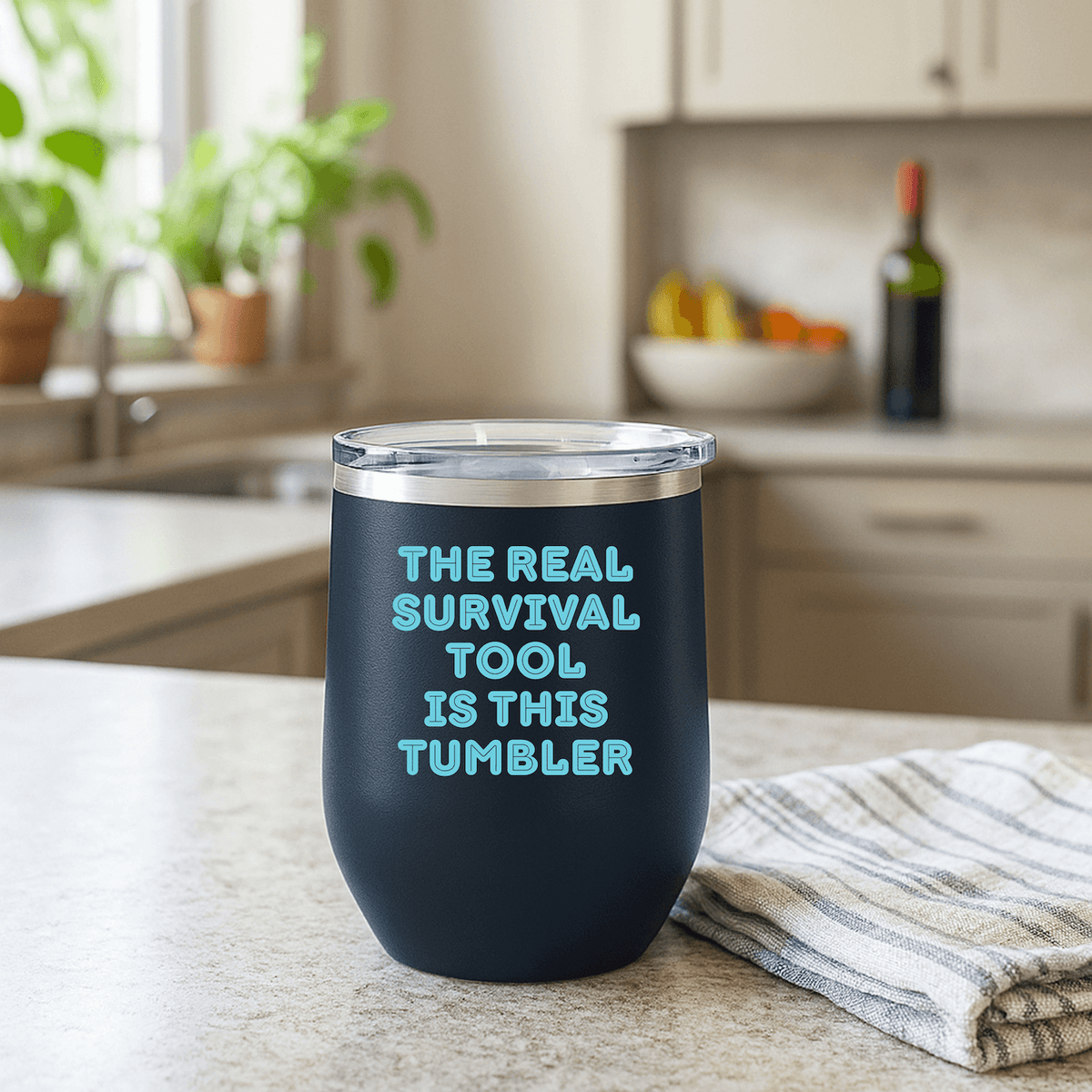 The Real Survival Tool Camping Wine Tumbler 12 oz on a kitchen counter with a striped towel.